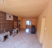 A room with tiled flooring, orange walls, and brick cladding in a family house.