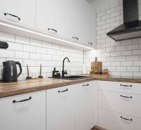 White kitchen unit with wood-patterned floor in a 2-room apartment.