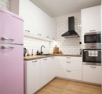 A kitchen in a 2-room apartment with a pink refrigerator and a wooden decor floor.