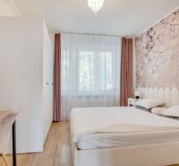 A bright bedroom with a bed and a subtle floral wallpaper decor in a two-room apartment.