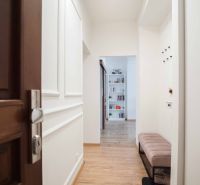 Hallway with wood-patterned flooring, open door, bookshelf, bench.