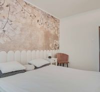 A bedroom in a two-room apartment with wall decorations of flowers and light furniture.