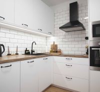 A kitchen in a 2-room apartment with white cabinets and a wood-patterned floor.