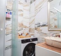 Bathroom of a 2-room apartment with a washing machine, sink, and marble tiles.