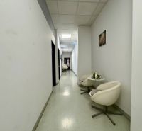A corridor in commercial premises with white walls and white chairs.