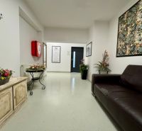 Reception in commercial premises with a dark sofa and floral decorations.