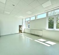 Bright commercial space with a sink and large windows, white walls.