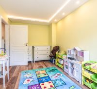 Children's room in a 4-room apartment with a colorful carpet and a wooden decor floor.