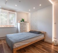 A bedroom with a gray curtain, a dresser, and a bed in a 4-room apartment with wood-patterned flooring.