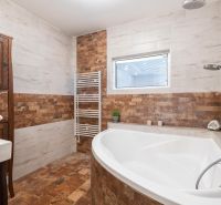 A bathroom in a 4-room apartment with a corner bathtub and brick tile cladding.