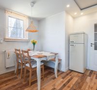 A bright kitchen with a table, chairs, flowers, and a wooden decor floor in a 4-room apartment.
