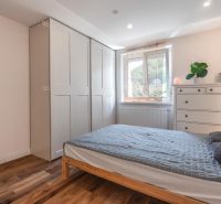 A bedroom in a 4-room apartment with a wooden decor floor, a bed, and a wardrobe.