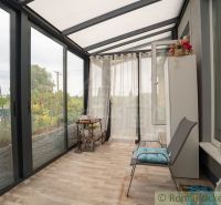 A glazed veranda with a wooden decor floor in a cottage.
