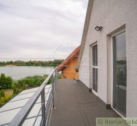 A cottage in Senec with a balcony and a view of the lake, surrounded by greenery.