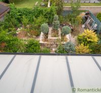 A garden by the cottage in Senec with rich greenery and a greenhouse.