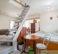 Interior of a cabin with a narrow staircase, bed, table, and floor with wooden decor.