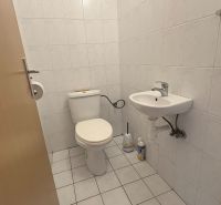 A toilet with basic equipment in a 2-room apartment, white ceramic tiles.