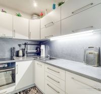A kitchen in a studio apartment with white cabinets and appliances on the countertop.