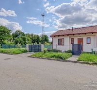 A family house on the street in Kátlovce with an antenna, grass, and a cloudy sky.