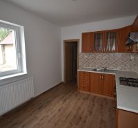 A kitchen in commercial premises with a wood-patterned floor and a gas stove.