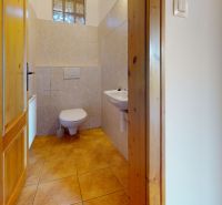 A toilet with light tiles and wooden doors in a family house.
