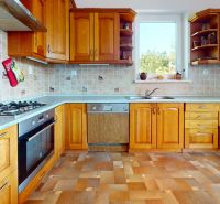 A kitchen in a family house with wooden cabinets and a floor with a wooden decor.