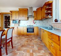 A kitchen in a family house with a wooden decor floor and wooden furniture.
