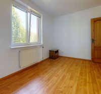 A room in a family house with a wooden decor floor, light streaming through the window.