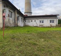 A building in Žiar nad Hronom with an industrial chimney, surrounded by a grassy area, suitable for warehouses and halls.