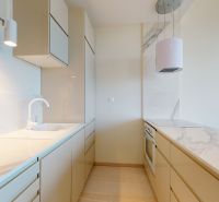 A kitchen in a 2-room apartment with white cabinets and a marble countertop.