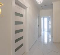 Hallway in a family house with white doors and marble floor.