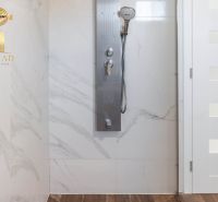 Shower enclosure with marble tiles and a wood-patterned floor in a family house.