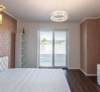 A bedroom with a soft bed, a wooden decor floor, and a wardrobe in a family house.
