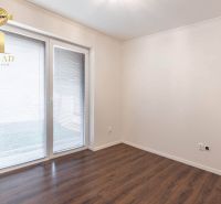 A room with a wooden decor floor and glass doors in a family house.