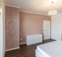 Interior of a family house with a wooden decor floor, white furniture, and a decorative wall.
