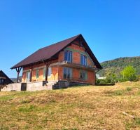A family house in Prestavlky with a sloped roof on a grassy plot with hills.