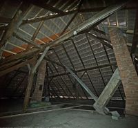 Attic in a family house with roof beams and a brick chimney.