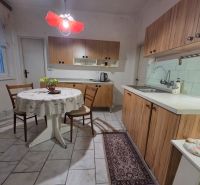A kitchen in a family house with wooden cabinets and a table with a tablecloth.