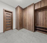 A hallway in a 2-room apartment with a wooden decor floor and a built-in wardrobe.