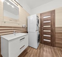 Bathroom with a washing machine and dryer in a 2-room apartment, floor with wooden decor.