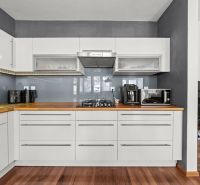 A kitchen in a 2-room apartment with a wooden decor floor and light furniture.