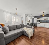 Living room and kitchen in a 2-room apartment with a wooden decor floor and light furniture.