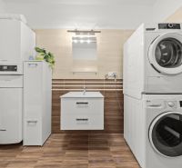 Bathroom with a washing machine and dryer, cabinet, and wooden decor flooring in a 2-room apartment.