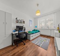 Children's room with a wooden decor floor in a 2-room apartment, a computer desk, and a bed.