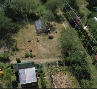 Gardens in Detva with wooden structures, trees, and cultivation areas.