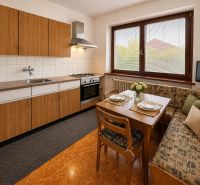 A kitchen in a family house with a wooden decor floor, a dining table, and a corner bench.