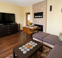 Living room in a family house with a wooden decor floor, a sofa, and a large television.