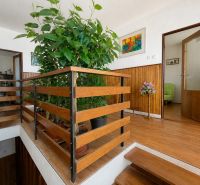 A hallway in a family house with a wooden decor floor and green plants.