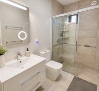 A bathroom in a family house with a sink, shower, and LED lighting.