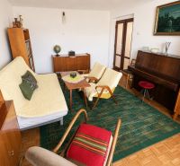 Living room with a piano and wood-patterned flooring in a family house.